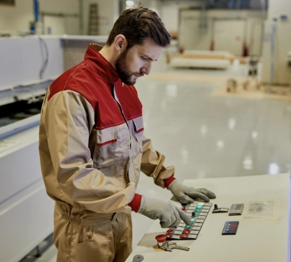 Operador industrial utilizando un panel de control para manejar una máquina de producción.